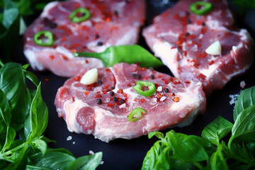Fresh raw meat steak with spices and fresh basil.