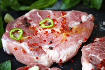 Fresh raw meat steak with spices and fresh basil.