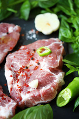 Fresh raw meat steak with spices and fresh basil.