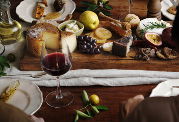 People eating a platter of cheese with seasonal fruits and wine