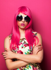 Young fashionable woman with pink hair and big sunglasses over pink background