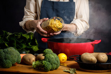 A woman cooking boils pasta in a saucepan with steam