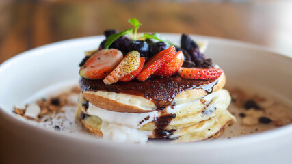 Pancakes with berries and fruits on a white plate