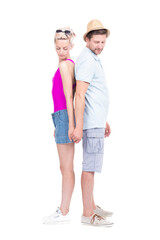 Vertical full length studio portrait of romantic young man and woman wearing summer outfits standing back to back holding hands, white background