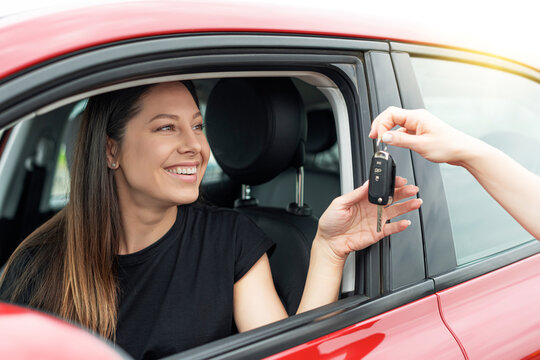 An attractive woman in a car gets the car keys. Rent or purchase of auto - concept.