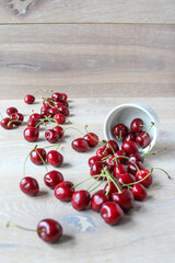 Fresh ripe berries. Pile of cherry on rustic wooden background. Cherries spilled out of a white bowl.