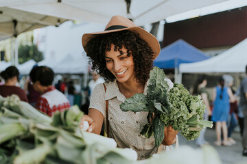 Beautiful woman buying kale at a farmers market - obrazy, fototapety, plakaty