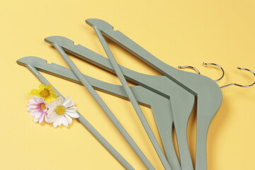 Green clothes hanger isolated on yellow background. Hanger made of wood with a simple motif.