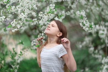 Fototapeta premium Adorable European kid girl with cherry blossom flowers, spring and self-care, tender child girl photo, childhood