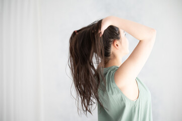Fototapeta premium ヘアケアなどに使えそうな髪の毛をかきあげる後ろ姿の美しい女性2 左あきコピースペース