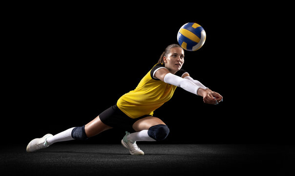 Female professional volleyball player with ball isolated on black studio background. The athlete, exercise, action, sport, healthy lifestyle, training, fitness concept. - Powered by Adobe