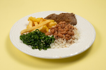 typical Brazilian basic dish with rice, beans, steak, french fries and braised cabbage