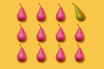 Pattern of pink painted pears on vibrant yellow background with one green pear. Differentiation and unique idea. Creative fruit food texture concept.
