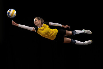 Female professional volleyball player with ball isolated on black studio background. The athlete,...