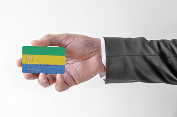 Bank credit plastic card with flag of Gabon holding man in elegant suit