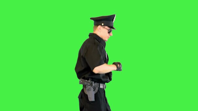 Young fully equipped policeman runs on a Green Screen, Chroma Key.