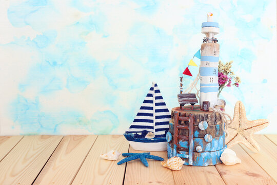 Nautical concept with sea life style objects as boat, driftwood beach house, seashells and starfish over wooden table