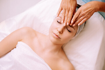 Close-up of young smiling young woman getting spa massage treatment at beauty spa salon. Spa skin and body care. Facial care. Cosmetology 