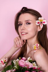 naked skinny girl holding flowers on a pink background. brunette