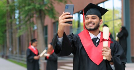 Selfie with diploma. Happy multiracial student boy being happy at his graduation day. Excited man...