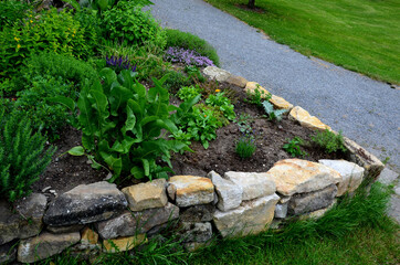 sandstone walls and stones in a flowerbed in a terraced terrain with stairs. flowering rock gardens...