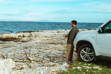 man standing near car at seaside. road trip concept