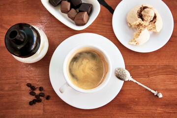 Cup of americano on wooden table with cookie and chocolate.