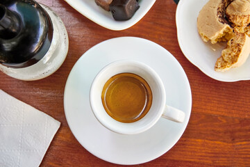 Cup of espresso on wooden table with cookie and chocolate.