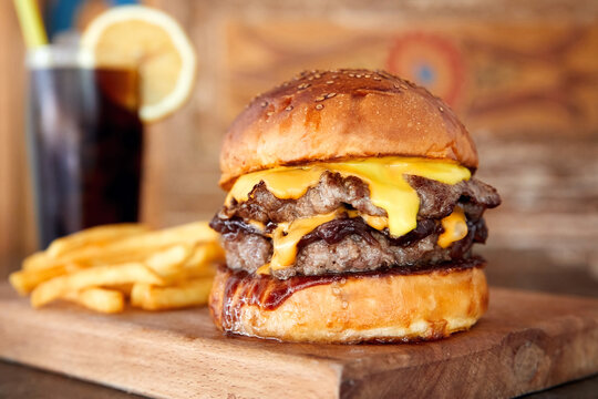 Delicious homemade cheeseburger or hamburger on wooden tray with coke and fires.