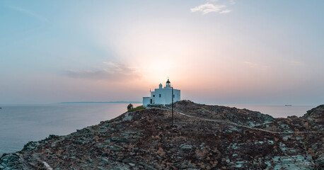 Fototapeta na wymiar Greece, Kea Tzia island. Lighthouse on rocky cape, sky, sea background.