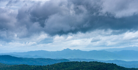 Overcast sky with dark cloud over mountain and forrest in windy and cloudy day.
