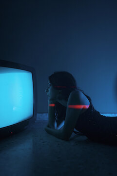 Woman lying down near old television in darkness