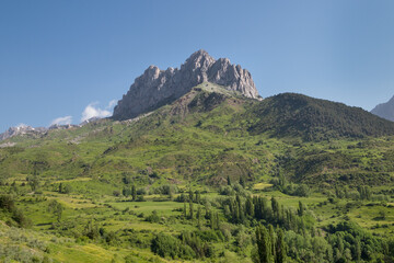 View of the rock formation Peña Foratata protruding from the surrounding meadows and forests, in the Tena Valley in the Spanish Pyrenees, Huesca, Spain