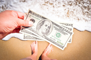 Girl holding money bill of 300 dollars on background of sea ocean