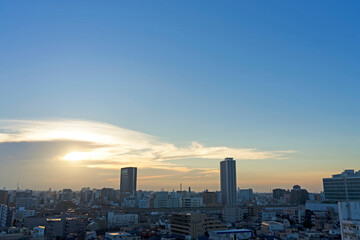 Fototapeta premium 雲間から見える夕日と街