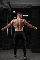Fototapeta na wymiar power muscular bodybuilder guy doing pullups in gym. Fitness man pumping up lats muscles. Fitness and bodybuilding training health lifestyle concept