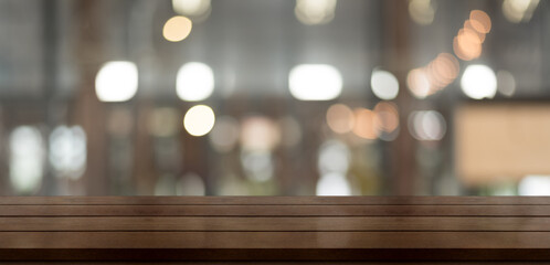 Empty wooden table top with lights bokeh on blur restaurant background.