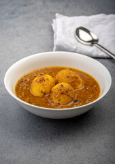Fried egg curry or anda masala served in a white bowl and copy space