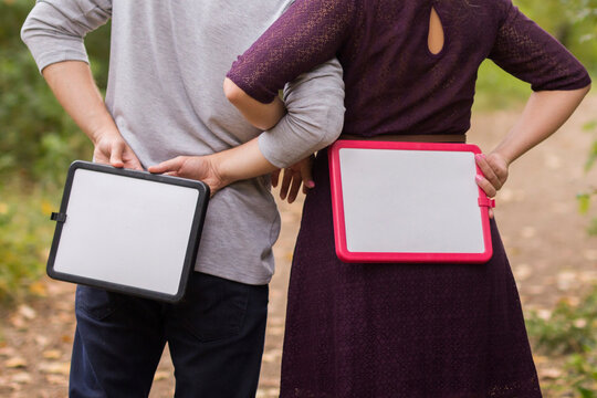 woman and man stand backwards and hold with plates love angagement