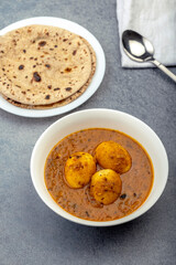 Fried egg curry or Anda Masala served in a bowl with chapati 