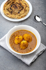 Fried egg curry or Anda Masala served in a bowl with  lachha parantha