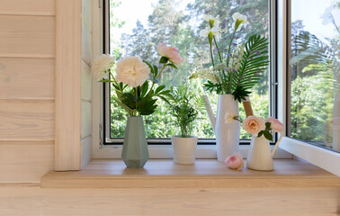 White window with mosquito net in a rustic wooden house overlooking the garden. Bouquet of white irises and lupins in watering can on the windowsill