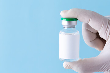 Medicine bottle for injection, Medical glass vial for vaccination. Science equipment, liquid drug or vaccine from treatment, flu in laboratory, hospital or pharmacy, copy space blue background.
