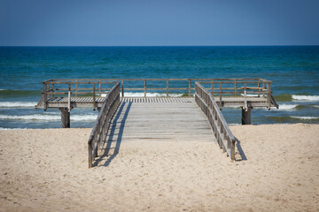 Wooden empty jetty or pier and beach by sunny sea. Travel, tourism and summer time