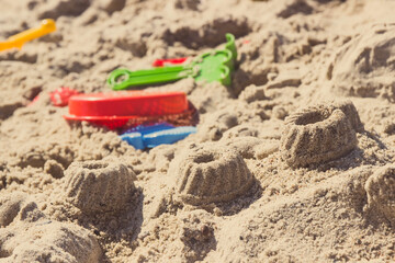 Different shapes made of sand and children toys for playing on beach. Vacation time and child development
