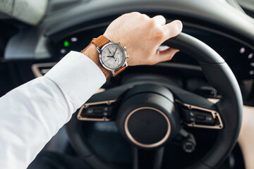 A man holding steering while while driving an expensive car