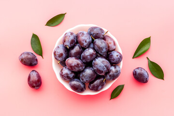 Ripe garden plums in bowl. Cherry fruit with leaves. Top view