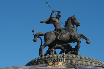 Obraz premium Saint George strikes the Serpent with a spear. St. George the Victorious is a symbol of the city of Moscow. On the spherical dome of the Okhotny Ryad Shopping Center n the Manezhnaya Square