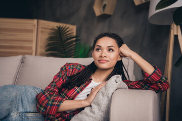 Photo of dreamy young afro american woman look away lie sofa relax free time inside house indoors apartment