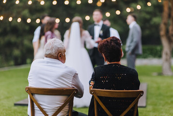 Old pensioners, grandfather and grandmother, sit on a wooden chair against the backdrop of a...